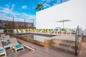 ein Pool auf dem Dach eines Gebäudes mit Stühlen und einem Sonnenschirm in der Unterkunft Iberostar Waves Las Dalias All Inclusive in Adeje + 74 Fotos
