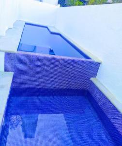 a swimming pool with a blue tiled floor and stairs at VILLA COSTERA HOTEL BOUTIQUE in Acapulco