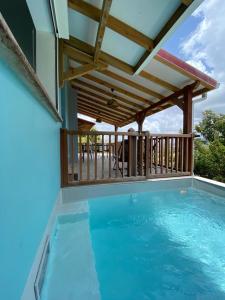 a large swimming pool with a wooden deck and a swimming poolvisor at La Maison in Les Trois-Îlets