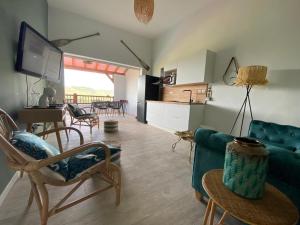 a living room with a couch and chairs and a kitchen at La Maison in Les Trois-Îlets