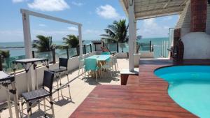 une terrasse avec une piscine, des tables et des chaises dans l'établissement Apartamento Duplex beira Mar, à Nísia Floresta