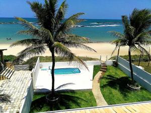 a swimming pool next to a beach with two palm trees at Apartamento Duplex beira Mar in Nísia Floresta