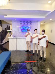 three men wearing face masks standing in a lobby at Hotel VGO in Kuala Lumpur