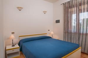 a bedroom with a blue bed and a window at Residence Il Vascello in Costa Rei