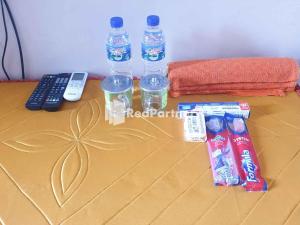 a table with a remote control and two water bottles at Hotel Gloria Borong Mitra RedDoorz 