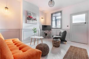 ein Wohnzimmer mit einem orangenen Sofa und Stühlen in der Unterkunft Guest Homes - Barton Road Retreat in Hereford