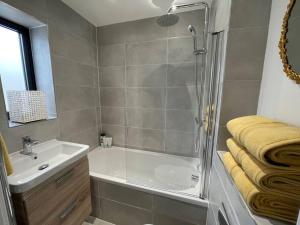 La salle de bains est pourvue d'une douche, d'une baignoire et d'un lavabo. dans l'établissement Salt Yard Cottage No 3, à Whitstable