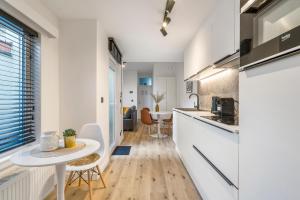a kitchen with white counters and a table in a room at Cosy, furnished & renovated flat with outside lounge in Ghent