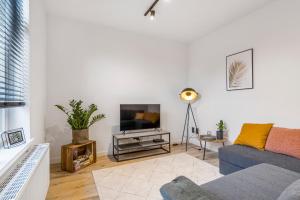 a living room with a blue couch and a tv at Cosy, furnished & renovated flat with outside lounge in Ghent