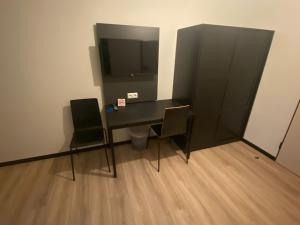 un escritorio negro con 2 sillas y un monitor de ordenador en Rheinsteig Quartier by bestprice Hotels en Bendorf