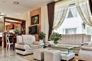 sala de estar con muebles blancos y mesa de cristal en villa Trung Nghĩa 5, en Da Lat
