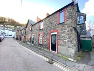 un antiguo edificio de piedra con persianas rojas en una calle en 21 Cross Street en Lynton