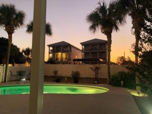 a house with palm trees in front of a swimming pool at PRIVATE HEATED POOL, GOLF CART & WALK to THE SUGAR SAND BEACH in DESTIN in Destin