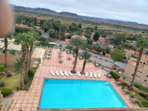 uma vista sobre uma piscina com cadeiras e palmeiras em Kenzi Azghor em Ouarzazate