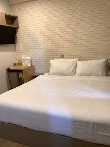 ein großes weißes Bett in einem Zimmer mit Ziegelwand in der Unterkunft CR.HOTEL in Makkasan