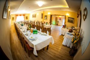 a long dining room with white tables and chairs at Piastun SPA&Wellness Krynica-Zdrój in Krynica Zdrój