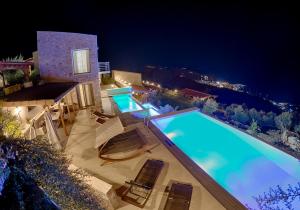 ein Pool mit Stühlen und ein Haus in der Nacht in der Unterkunft Sky Sea Resort Skiathos in Skiathos-Stadt