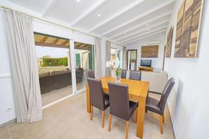 una sala da pranzo con tavolo e sedie in legno di Villa Ambient / Sa Finqueta a Playa de Muro