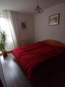 - une chambre avec un lit rouge et une plante en pot dans l'établissement Grüne Stadtwohnung, à Sarrebruck