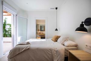 a white bedroom with a bed and a large window at Agradable casa con patio interior. in Molina de Segura