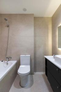 a bathroom with a toilet and a tub and a sink at Agradable casa con patio interior. in Molina de Segura