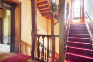 - un escalier dans une maison dotée de moquette rouge et de plafonds en bois dans l'établissement Manoir de Truhelin, à 2 pas du Golfe du Morbihan, à Arradon