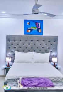 um quarto com uma cama grande e uma pintura azul por cima. em D White Villas em Old Yundum