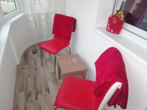 two red chairs and a table in a room at Apartament Racadau in Braşov