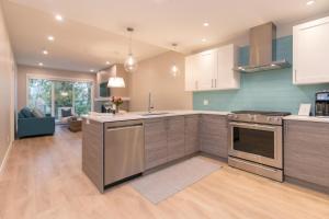a kitchen with stainless steel appliances and a living room at Coffee With A View, Brand New One Bedroom At Sooke Harbour in Sooke