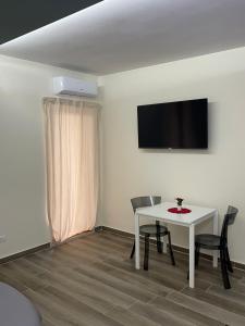 Cette chambre comprend une table et des chaises blanches ainsi qu'une télévision. dans l'établissement B&B MIRAGE, à Bari