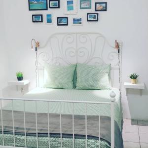 a white bed with green pillows and pictures on the wall at Little Surf House Hostel in Las Palmas de Gran Canaria