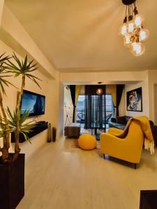 a living room with a yellow couch and a palm tree at Sandev Apartments in Štip
