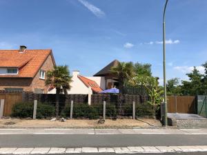 a house with a fence in front of a house at B&B Kudita in De Panne