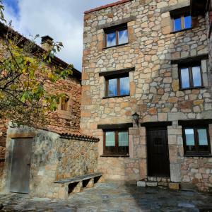 ein altes Steingebäude mit einer Bank davor in der Unterkunft Casa Rural La Colmena in Condemios de Abajo