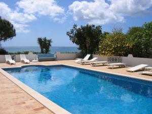 een zwembad met ligstoelen en de oceaan bij BUGANVÍLEA - Vivenda johanna in Lagos