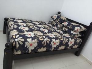 a bed with a black frame with flowers on it at HOMESTAY KUANTAN INDERA SEMPURNA 2 in Kuantan