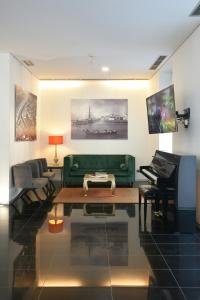 a living room with a green couch and a piano at Lazza Hotel in Figueira da Foz