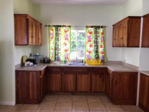 a kitchen with wooden cabinets and a sink and a window at Beautiful 2-Bed Apartment in sunny Jamaica in Silver Sands