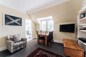 uma sala de estar com uma mesa e cadeiras e uma televisão em Luxury Inverness central apartment private parking em Inverness