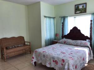 a bedroom with a bed and a chair and a window at Beautiful 2-Bed Apartment in sunny Jamaica in Silver Sands