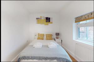 a white bedroom with a bed with two towels on it at New Spacious 1 bed studio flat in Aldgate in London