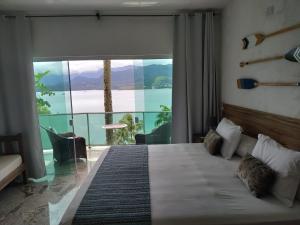 1 dormitorio con 1 cama y vistas al océano en Suites na Casa da Praia, en Ilhabela
