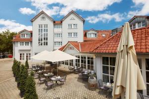 ein Hotel mit einer Terrasse mit Stühlen und Sonnenschirmen in der Unterkunft nestor Hotel Neckarsulm in Neckarsulm