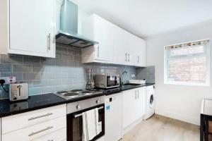 a kitchen with white cabinets and a black counter top at Modern split level 1 bedroom flat in Aldgate in London