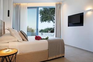 a bedroom with a bed and a large window at Oasis Beach Hotel in Skala
