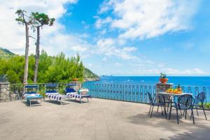 a patio with chairs and a table and the ocean at Villa Russo - De Vivo Realty Nerano in Nerano