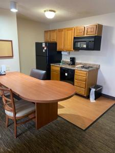 a kitchen with a wooden table and a kitchen with a black refrigerator at Candlewood Williamsport, an IHG Hotel in Williamsport