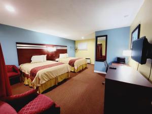 a hotel room with two beds and a flat screen tv at Bassett Motel in Williamsburg