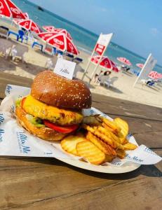 a hamburger and french fries on a plate next to the beach at beach front tel aviv bat yam apartment -hotel 39 in Bat Yam