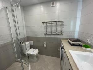 a bathroom with a toilet and a sink and a shower at Стильна квартира в новому будинку, поряд центр та р. Дніпро in Cherkasy +5 photos